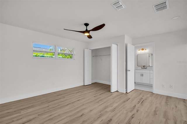 unfurnished bedroom with light wood-style flooring, a sink, visible vents, and baseboards