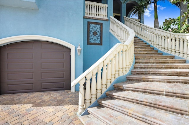 entrance to property with a garage and stucco siding