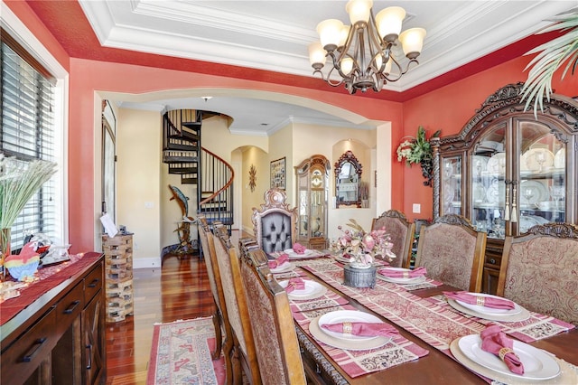 dining area with arched walkways, crown molding, wood finished floors, and an inviting chandelier