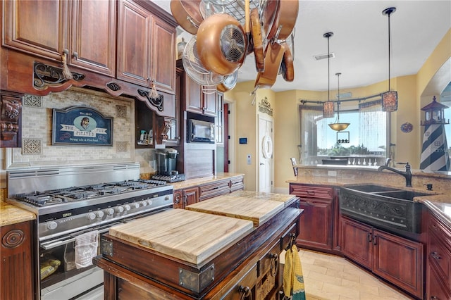 kitchen with butcher block countertops, a sink, visible vents, backsplash, and gas stove