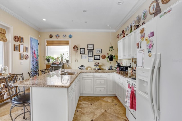 kitchen featuring a sink, light stone countertops, white appliances, a peninsula, and a kitchen breakfast bar