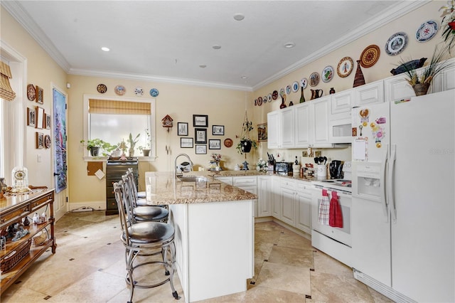 kitchen with light stone counters, crown molding, white cabinetry, white appliances, and a kitchen breakfast bar