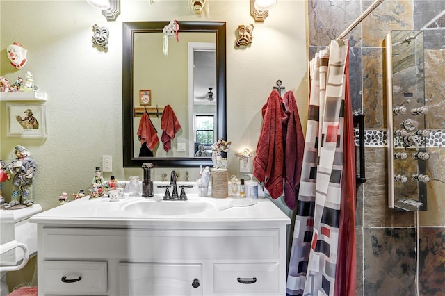 bathroom with a textured wall, tiled shower, and vanity