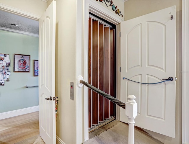 hall featuring a textured ceiling, light wood-style floors, and baseboards