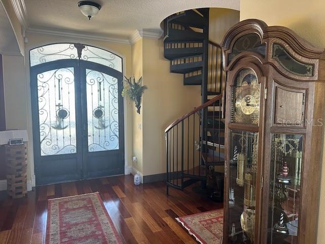 foyer featuring french doors, crown molding, stairway, and wood finished floors