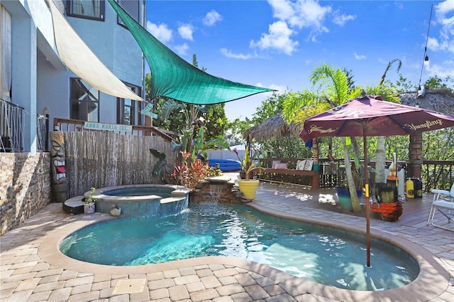 view of swimming pool featuring a pool with connected hot tub, fence, and a patio