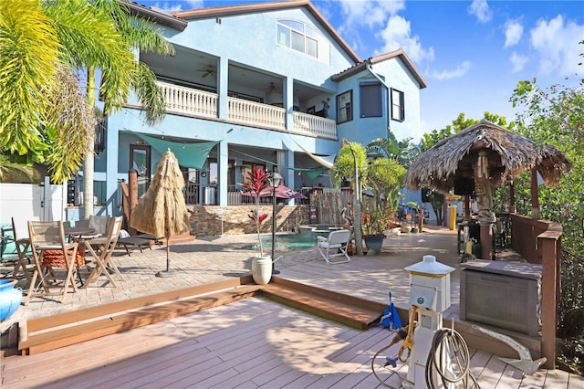 back of house featuring stucco siding, ceiling fan, fence, a deck, and outdoor dining space