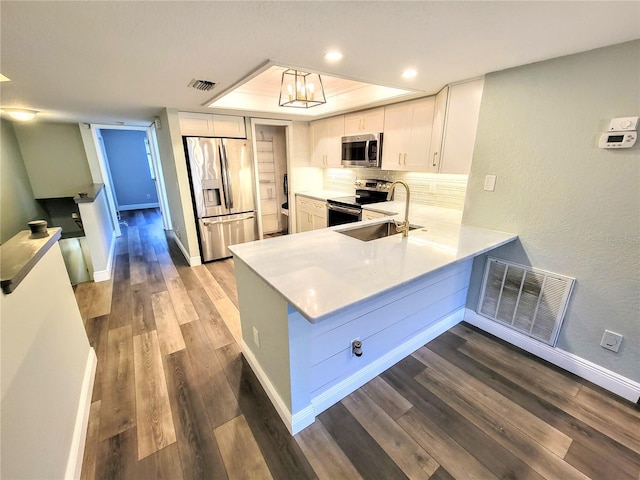 kitchen with stainless steel appliances, dark wood-style flooring, a sink, and visible vents