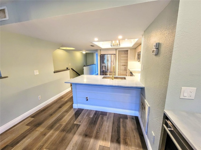 kitchen with baseboards, stainless steel fridge with ice dispenser, dark wood-type flooring, a peninsula, and light countertops