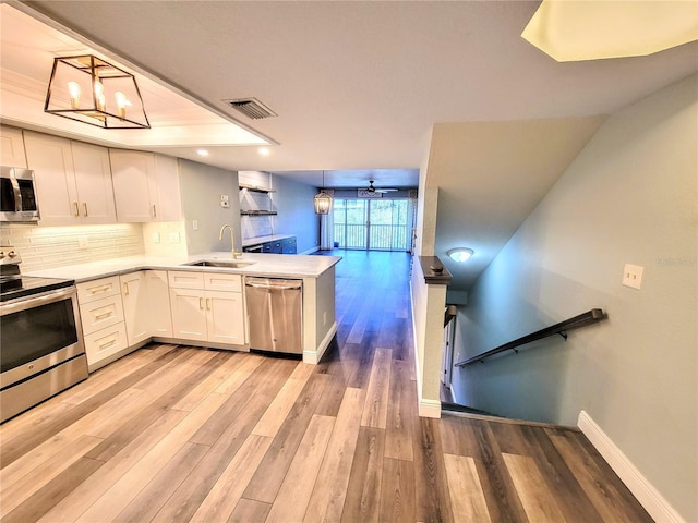 kitchen with tasteful backsplash, visible vents, appliances with stainless steel finishes, a sink, and a peninsula