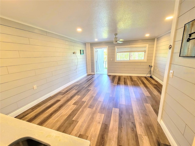 empty room featuring a textured ceiling, recessed lighting, wood finished floors, and baseboards