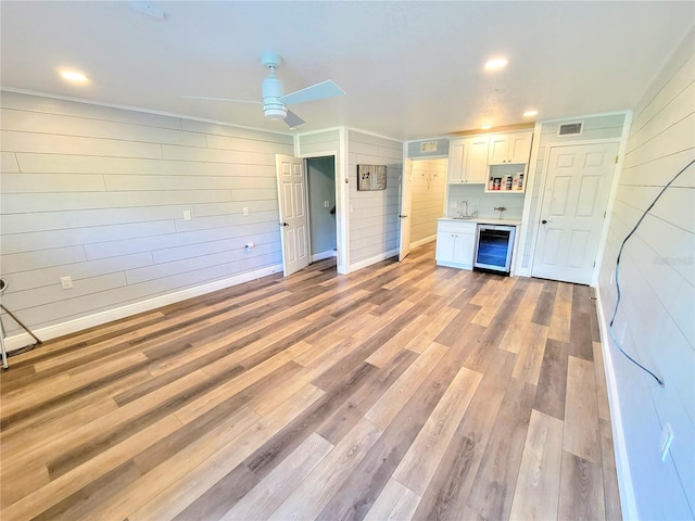 interior space featuring light wood finished floors, visible vents, white cabinetry, a sink, and beverage cooler