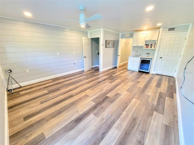 kitchen with visible vents, white cabinetry, a sink, light wood-type flooring, and beverage cooler