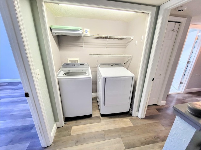 laundry room featuring light wood finished floors, washing machine and dryer, laundry area, and baseboards