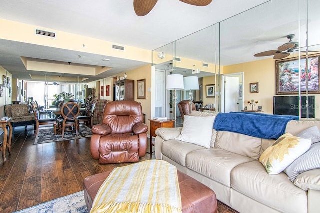 living room with hardwood / wood-style flooring, ceiling fan, and visible vents