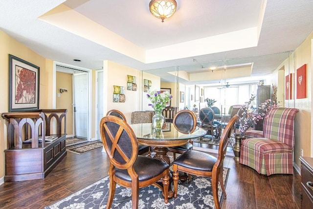 dining room with dark wood-type flooring and a tray ceiling