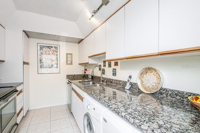 kitchen featuring light tile patterned floors, a sink, white cabinets, appliances with stainless steel finishes, and washer / dryer