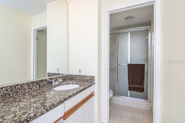 bathroom with vanity, a shower stall, toilet, and tile patterned floors