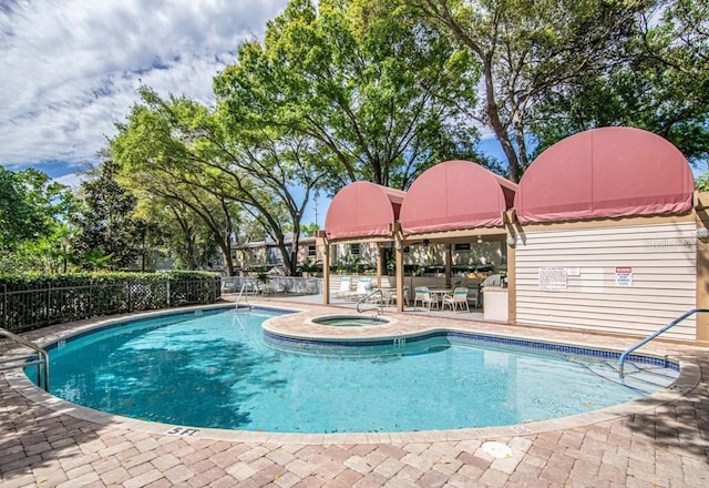 community pool featuring a patio area, a hot tub, and fence