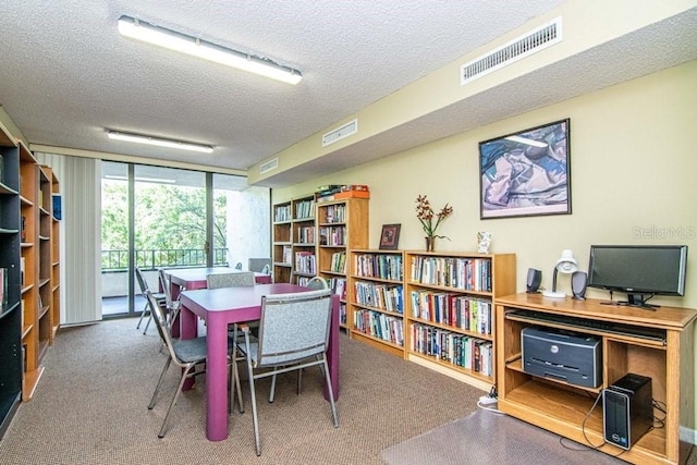 office with floor to ceiling windows, visible vents, a textured ceiling, and carpet flooring