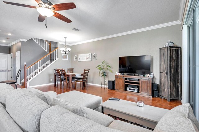 living area featuring crown molding, light wood finished floors, visible vents, stairway, and baseboards