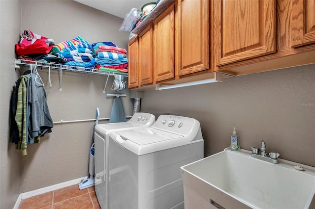 clothes washing area with light tile patterned floors, a sink, baseboards, independent washer and dryer, and cabinet space