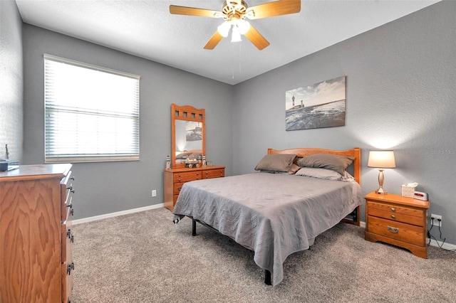 carpeted bedroom with ceiling fan and baseboards