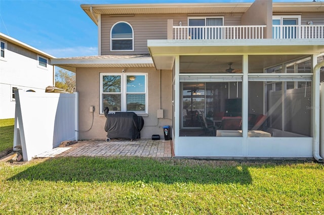 back of property featuring a patio, a lawn, a sunroom, and stucco siding