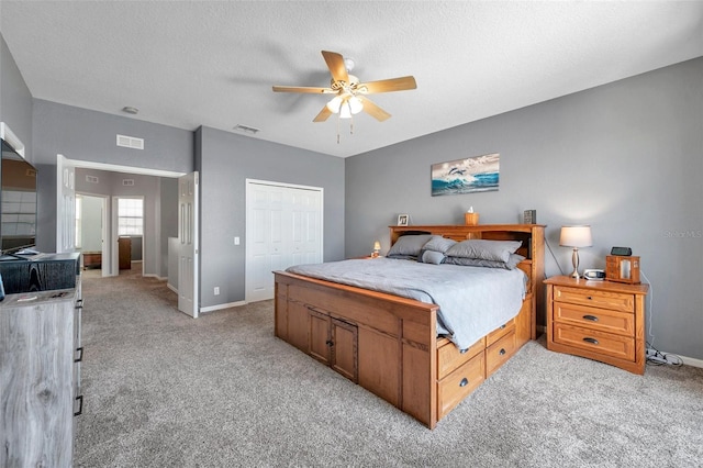 bedroom with light carpet, a textured ceiling, visible vents, and a closet