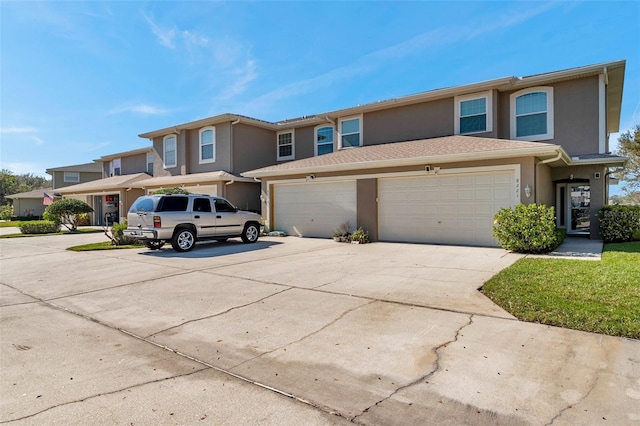 multi unit property with a garage, driveway, and stucco siding