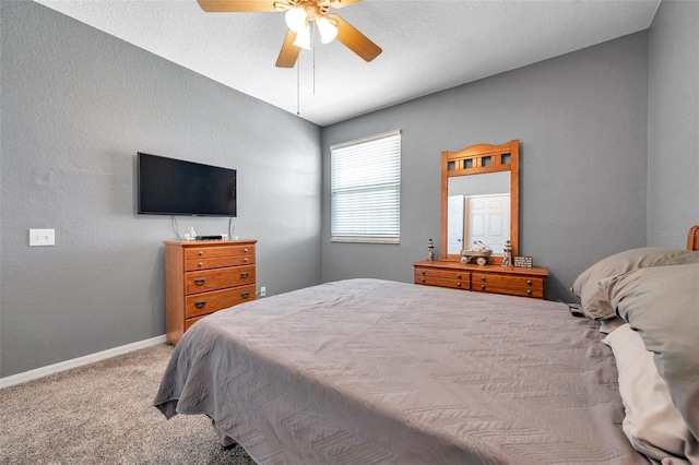 carpeted bedroom with ceiling fan, a textured wall, and baseboards