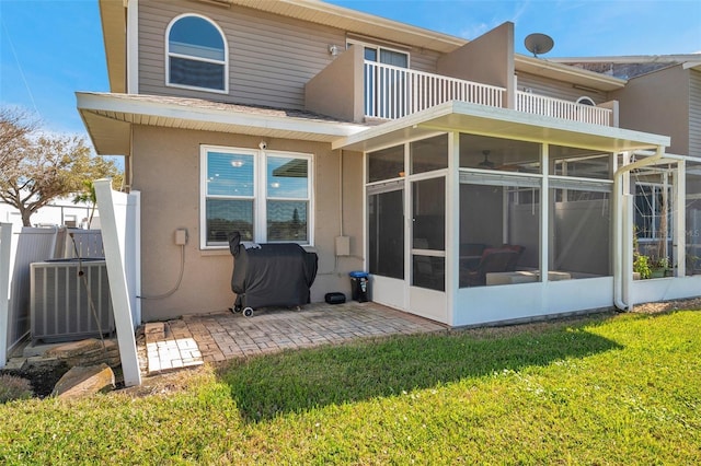 back of house featuring a balcony, central air condition unit, a sunroom, stucco siding, and a patio area