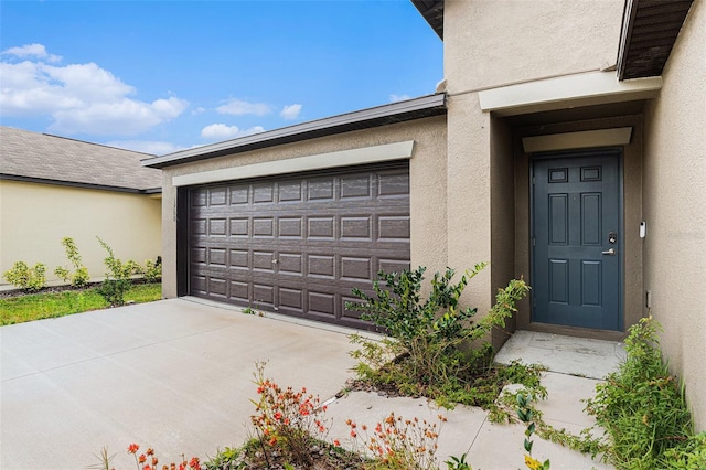 property entrance with driveway, an attached garage, and stucco siding