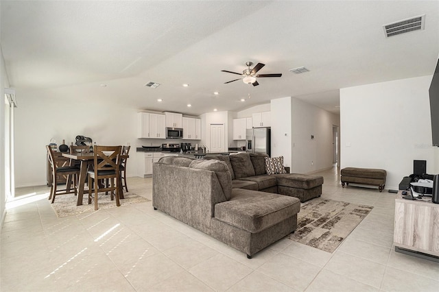 living room featuring lofted ceiling, light tile patterned flooring, visible vents, and a ceiling fan