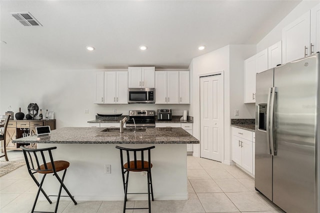 kitchen with stainless steel appliances, white cabinets, visible vents, and a kitchen breakfast bar