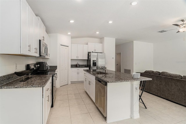 kitchen featuring a center island with sink, white cabinets, appliances with stainless steel finishes, open floor plan, and a sink