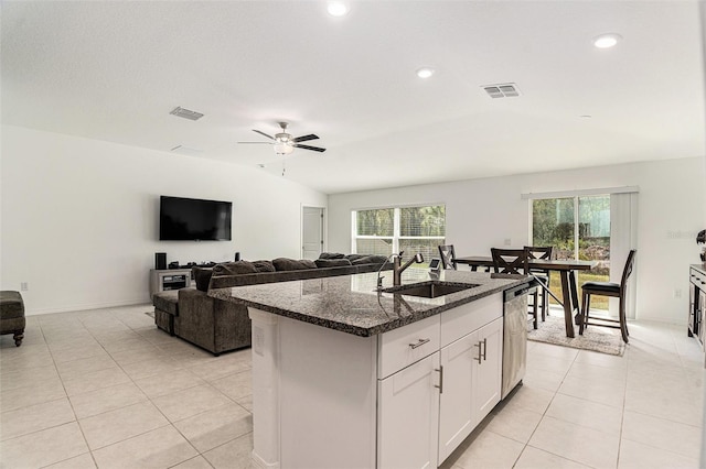 kitchen featuring light tile patterned floors, visible vents, a sink, dark stone counters, and dishwasher