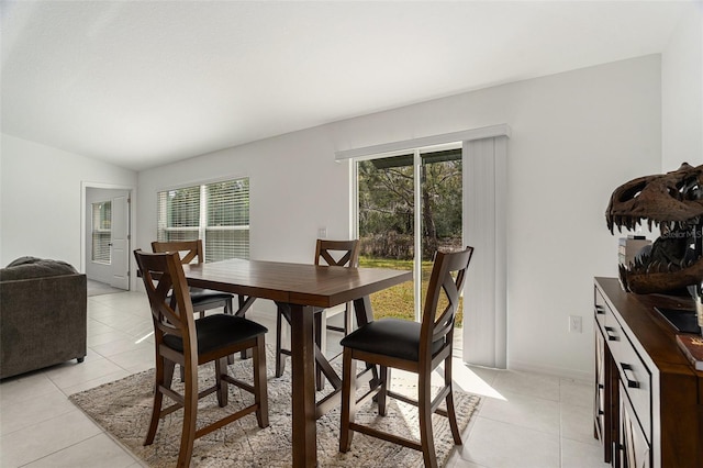 dining area with light tile patterned floors, vaulted ceiling, and baseboards