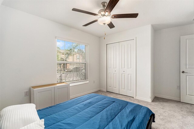 bedroom with a ceiling fan, a closet, light carpet, and baseboards