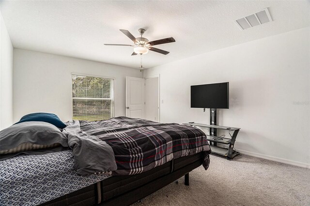 carpeted bedroom featuring a ceiling fan, visible vents, a textured ceiling, and baseboards