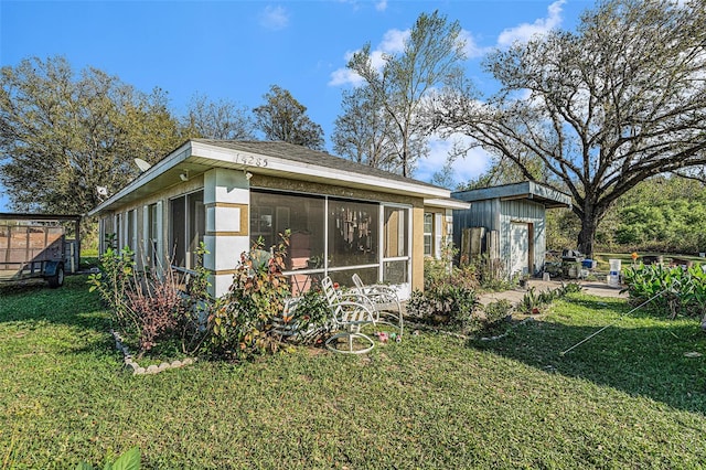 rear view of house with an outbuilding, a yard, and a sunroom