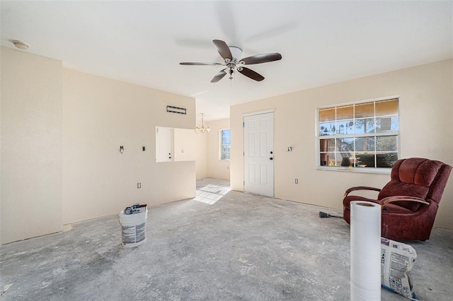 interior space featuring concrete flooring and ceiling fan with notable chandelier