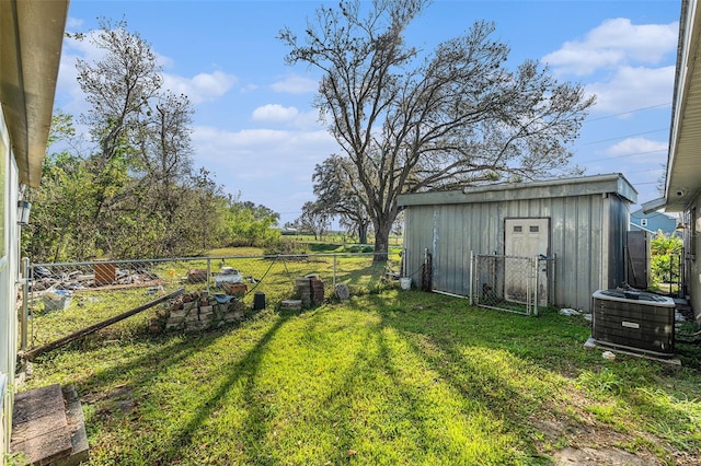 view of yard with an outbuilding, central AC, a shed, and fence