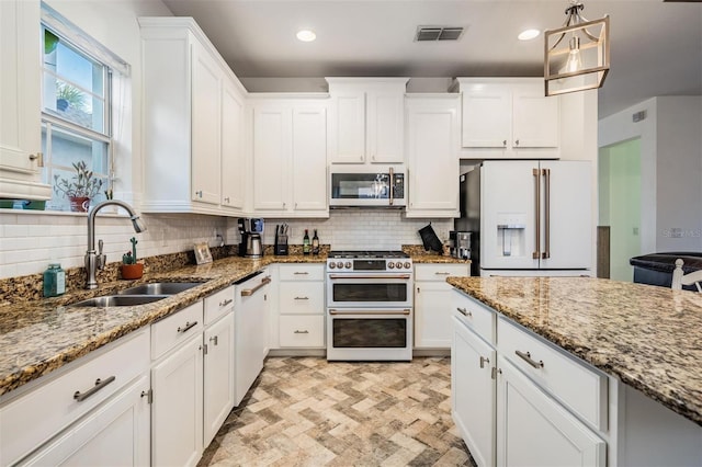 kitchen with visible vents, decorative backsplash, white cabinets, a sink, and white appliances