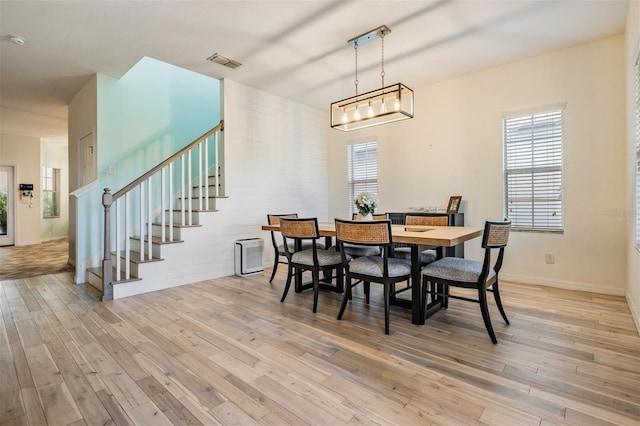 dining room with stairs, light wood-style flooring, visible vents, and a healthy amount of sunlight