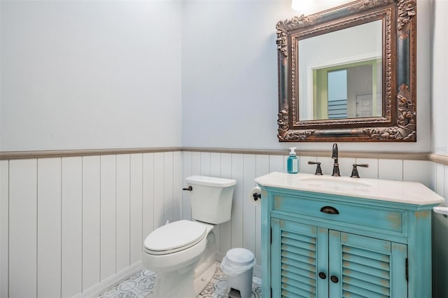 bathroom with a wainscoted wall, vanity, and toilet