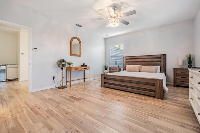 bedroom with visible vents, wine cooler, light wood-style flooring, and baseboards