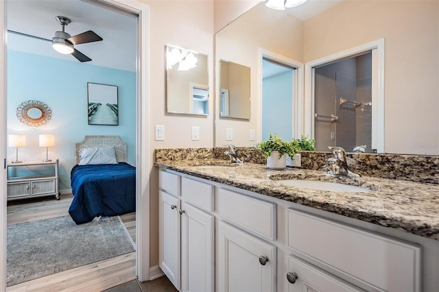 ensuite bathroom with double vanity, a sink, a tile shower, and wood finished floors