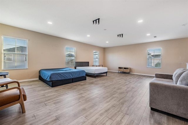 bedroom with light wood-type flooring, multiple windows, and baseboards