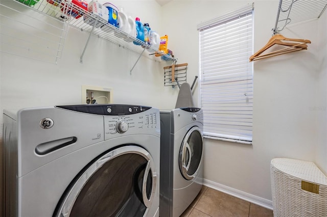 washroom featuring washing machine and dryer, laundry area, tile patterned flooring, and baseboards